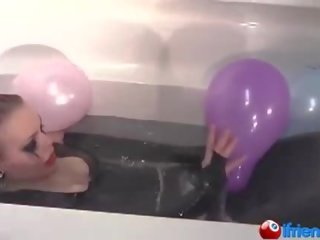 Latex dressed adolescent with balloons in a bathtub